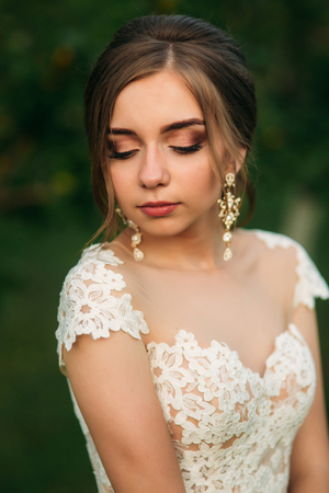 Young girl in wedding dress in park posing for photographer. Sunny weather, summer.の写真素材