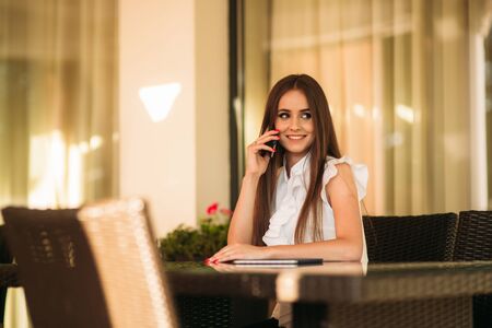 Business lady uses a tablet and phone to work. The girl in the cafe is smiling. Summerの写真素材