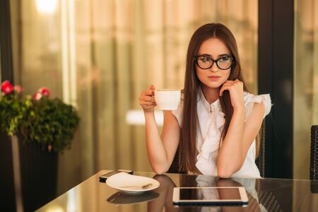 Business lady uses a tablet and phone to work. The girl in the cafe is smiling. Summerの写真素材