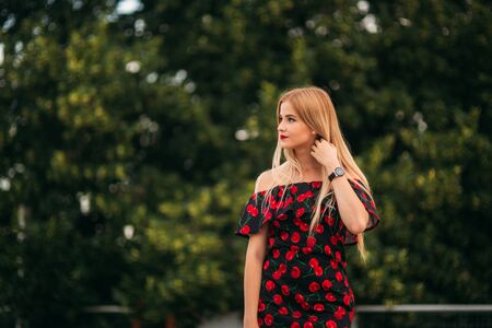 Beautiful girls posing for the photographer. Two sisters in black and red dress. Smile, sunny day, summer.の写真素材