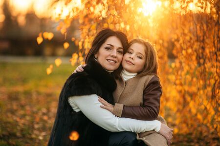 Little girl with mother walking in the park in autumn. Golden autumn.の写真素材