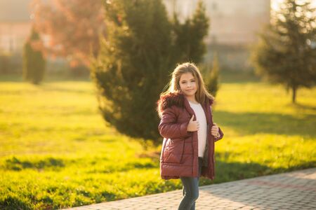 Little girl in autumn coat posing for photographer. Golden autumn.の写真素材