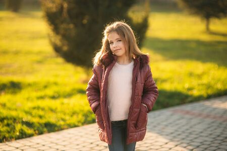 Little girl in autumn coat posing for photographer. Golden autumn.の写真素材