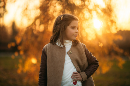 Little girl in autumn coat posing for photographer. Golden autumn.の写真素材