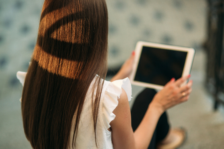 Young girl use a tablet and phone to work. The girl in the cafe is smilingの写真素材