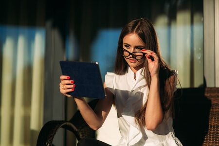 Young girl use a tablet and phone to work. The girl in the cafe is smilingの写真素材