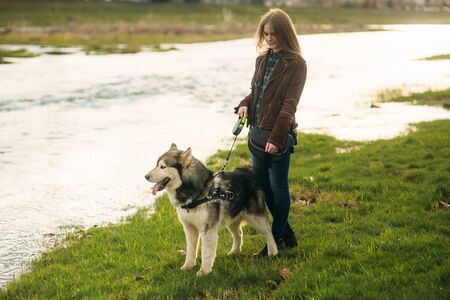 A beautiful girl is walking along the embankment. Blond hair and brown jacket.の写真素材