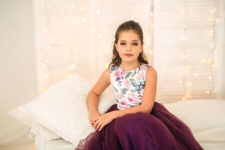 Beautiful girl in a purple dress and flower blouse posing for a photographer.の写真素材