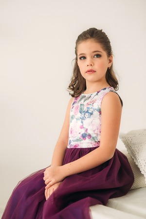 Beautiful girl in a purple dress and flower blouse posing for a photographer.の写真素材