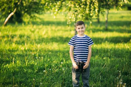Little boy in a striped t-shirt looks through binoculars .Spring, sunny weather.の写真素材