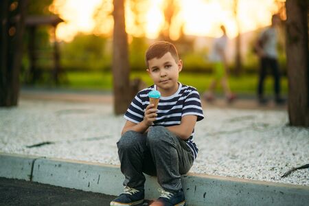 A little in a stripper t-shirt is eating blue ice cream.の写真素材