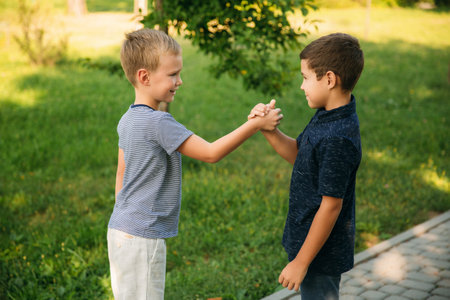 Two children are playing in the park. Two beautiful boys in T-shirts and shorts have fun smiling....