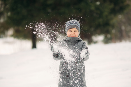 A little boy walks in the park in the winter weather, play snowballs and rejoiced. Waiting for Christmas moodの写真素材
