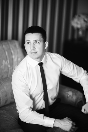 The groom is dressed at home in a suit. Cute groom posing for a photographerの写真素材
