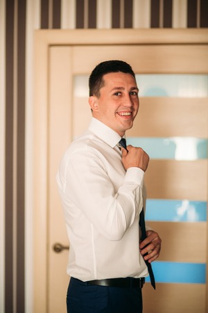 The groom is dressed at home in a suit. Cute groom posing for a photographerの写真素材