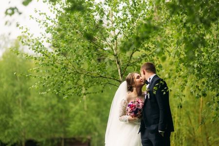The newlyweds are walking in the park on the wedding day. The bride and groom Enjoying at the wedding day. Sunny weather. Springの写真素材