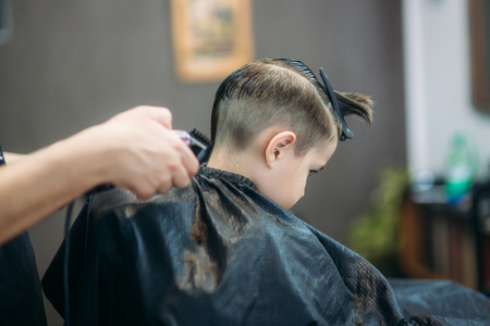 Little boy on a haircut in the barber sits on a chairの写真素材