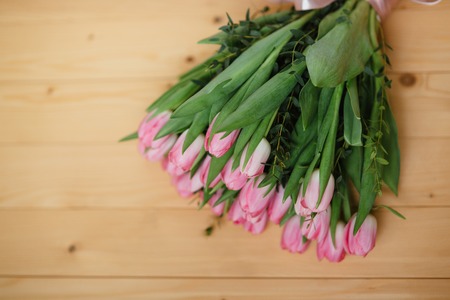 Bouquet of pink tulips and  with a beautiful bow on a wooden backgroundの写真素材