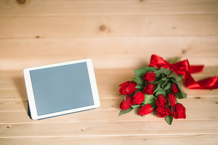 Beautiful red tulips and tablet on a wooden backgroundの写真素材