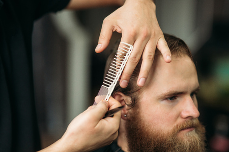 Barber using scissors and comb in barbershopの写真素材