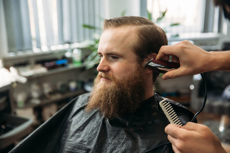 Bearded man having a haircut with a hair clippers