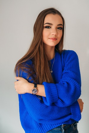Beautiful brunette girl with a lovely smile in a blue blouse posing for a photographer and showing her makeupの写真素材