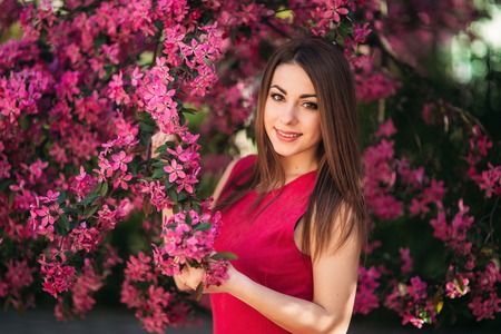 Young girl posing for a photo. Flowering pink trees in the background. Spring. Sakuraの写真素材