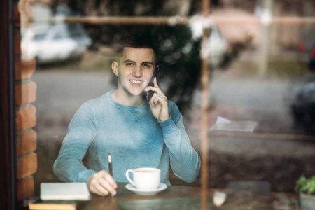 Man uses a laptop in a cafe while drinking coffeeの写真素材