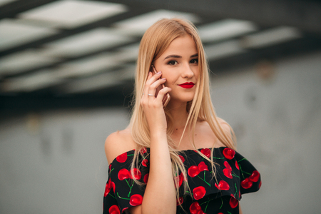 Blonde girl using phone and smilingの写真素材