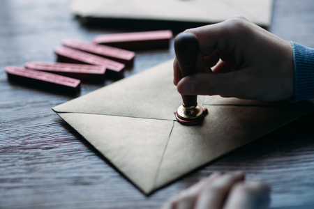 Man makes the stamp using sealing wax on the envelopeの写真素材