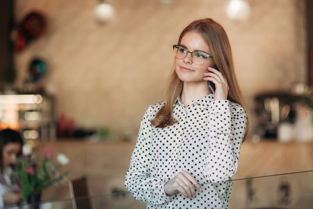 Blond Business lady with glasess use phone in cafeの写真素材