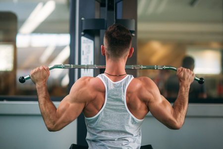 A young athlete trains in the gym. Shows the muscles of the back and chest