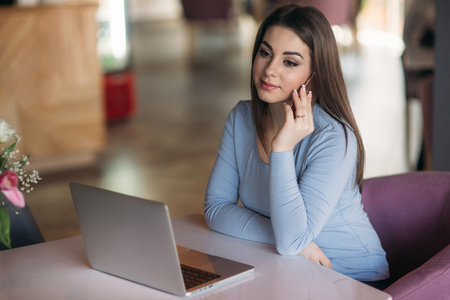 Beautiful brunette business woman use phone in a cafe with laptopの写真素材