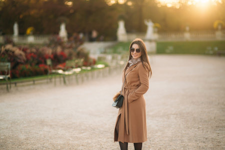 Stylish girl in coat posing for photographer. Park