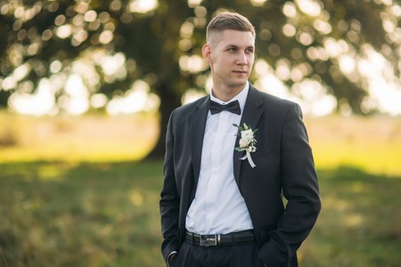 Groom standing in the middle of field in the background of big treeの写真素材