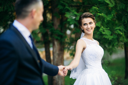 Young couple, bride and groom walking and enjoying their wedding day. Sunshine. Summerの写真素材