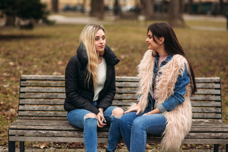 Two girls sitting on the bench outdoorsの写真素材