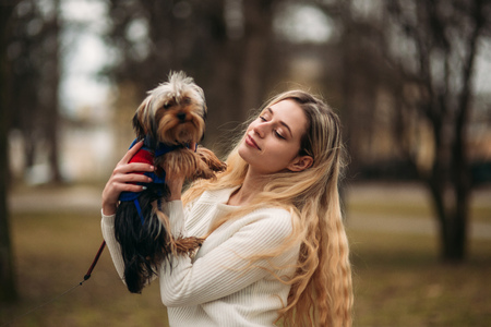 Blonde girl in the park in cloudy weather with dogの写真素材
