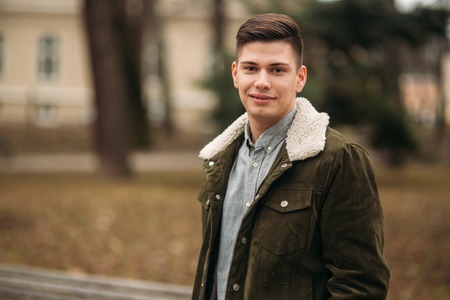 Nice guy sitting on the bench outdoors in cloudy weatherの写真素材