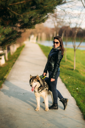 Beautiful brunette lady walking with a dog along the embankment. Beautiful husky dogの写真素材