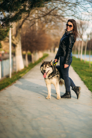 Beautiful brunette lady walking with a dog along the embankment. Beautiful husky dogの写真素材
