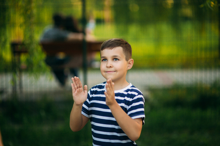 A little boy in a striped T-shirt standing in front of green background. Smiling and looking to the photographerの写真素材