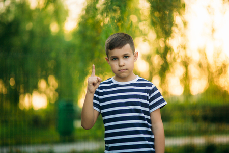 A little boy in a striped T-shirt standing in front of green background. Smiling and looking to the photographerの写真素材