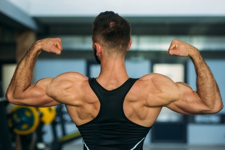 A young athlete trains in the gym. Shows the muscles of backの写真素材