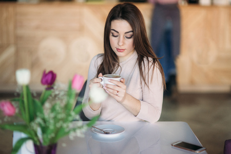 Beautiful girl siting in cafe and drinking cappuccinoの写真素材