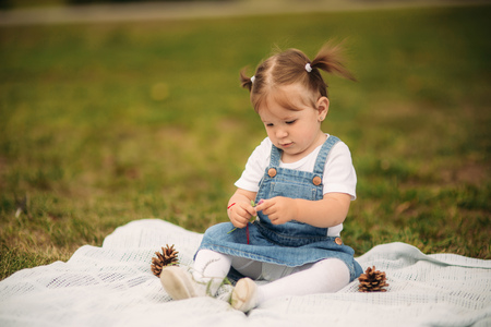 Little girl sitting in a park on a plaid and playingの写真素材