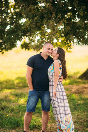 Handsome guy and an attractive girl hug each other near a large green tree. Love storyの写真素材