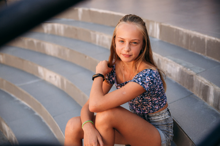 teenage female dressed in jeans sits on stairsの写真素材