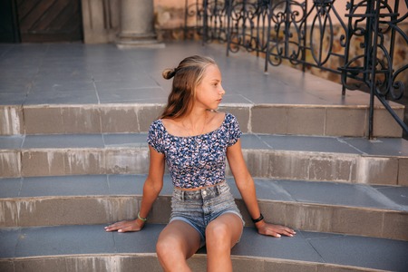 teenage female dressed in jeans sits on stairsの写真素材