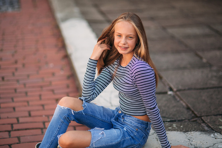 young teenage poses for photo. blonde girl in jeans and blouse. play with hairの写真素材
